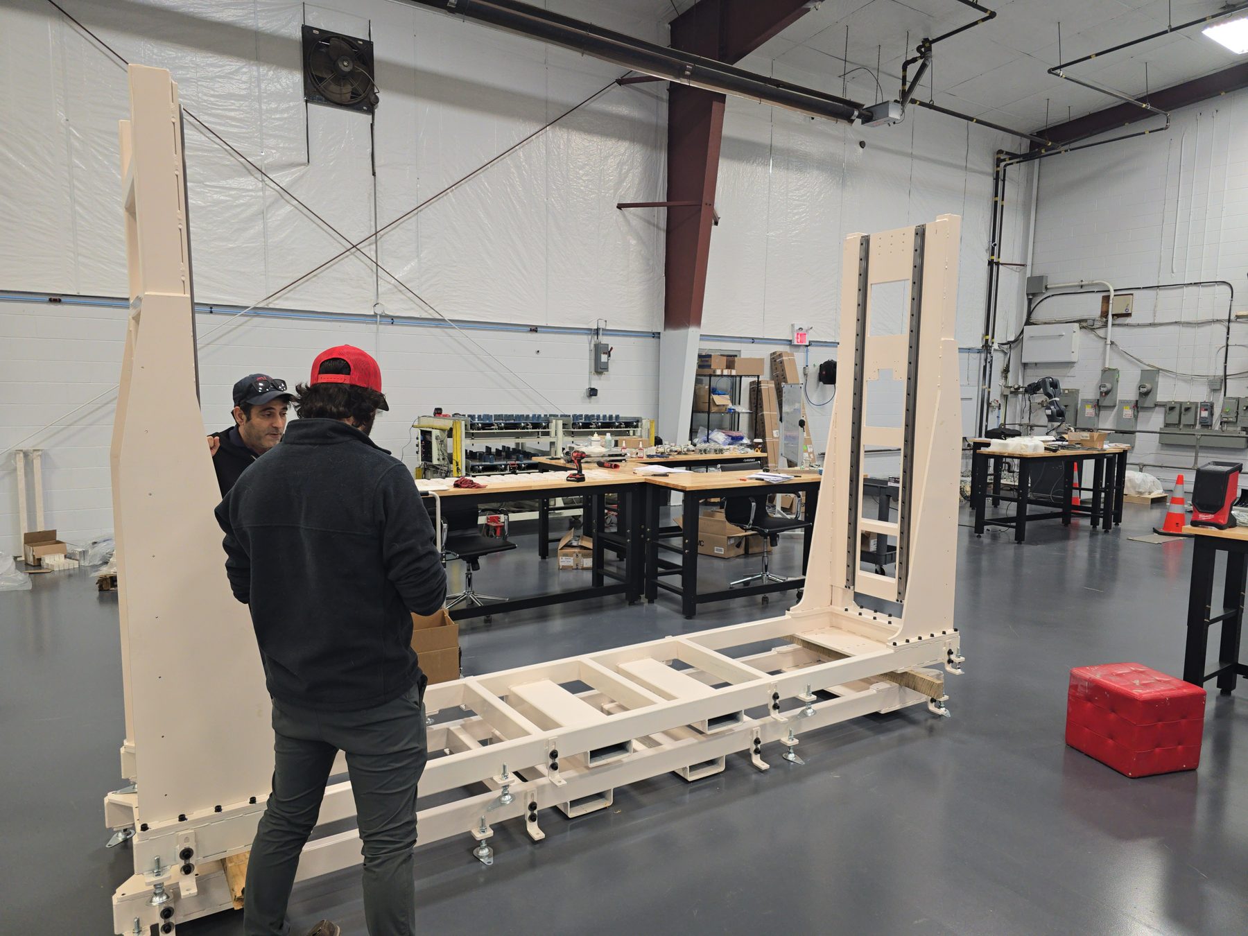 Two PH Engineering staff assembling a large powder-coated frame structure on the shop floor